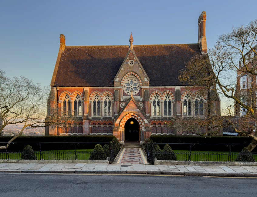 A historic brick church with Gothic architectural features, including pointed arches, intricate window tracery, and a large circular stained glass window above the main entrance. The building has a st