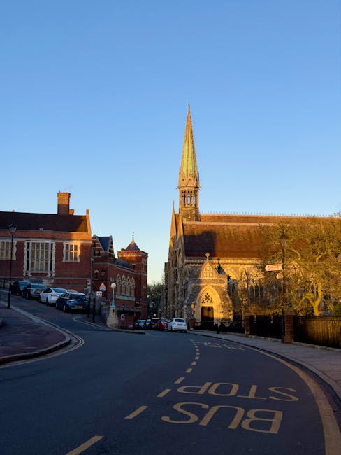 A historic brick church with Gothic architectural features, including pointed arches, intricate window tracery, and a large circular stained glass window above the main entrance. The building has a st